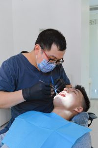 Smiling man getting his teeth checked at the dentist office